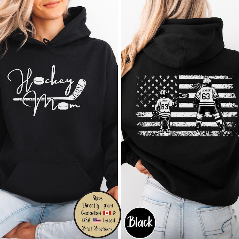 May include: Black hoodie with a front design that says "Hockey Mom" in white script with hockey stick and puck graphics. The back features an American flag design with hockey players and the number 63.