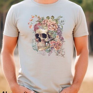 May include: A light gray t-shirt with a floral skull design. The skull is surrounded by pink, purple, and white flowers.