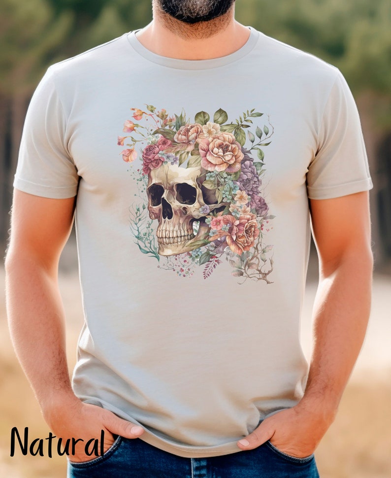 May include: A light gray t-shirt with a floral skull design. The skull is surrounded by pink, purple, and white flowers.