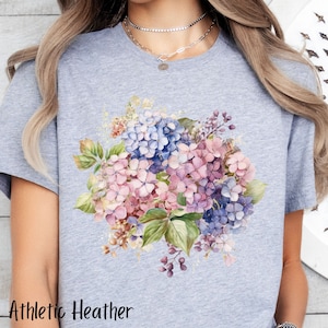 Peut inclure: Un t-shirt gris chin&eacute; avec un motif aquarelle d'un bouquet d'hortensias roses, violets et bleus.