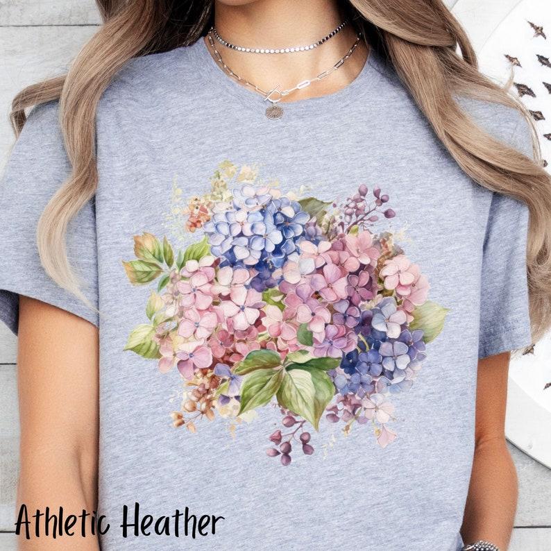 Peut inclure: Un t-shirt gris chin&eacute; avec un motif aquarelle d'un bouquet d'hortensias roses, violets et bleus.