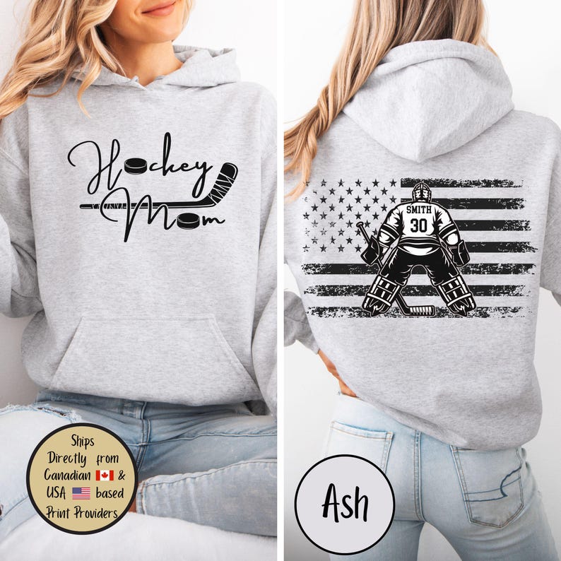 May include: Light gray hoodie with a front graphic that reads "Hockey Mom" with a hockey stick and puck. The back features a hockey goalie in front of a distressed American flag design. The goalie's jersey has the number 30 and the name "Smith".