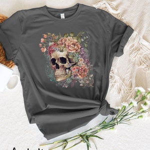 May include: A dark gray t-shirt with a floral skull design. The skull is surrounded by pink, purple, and white flowers.