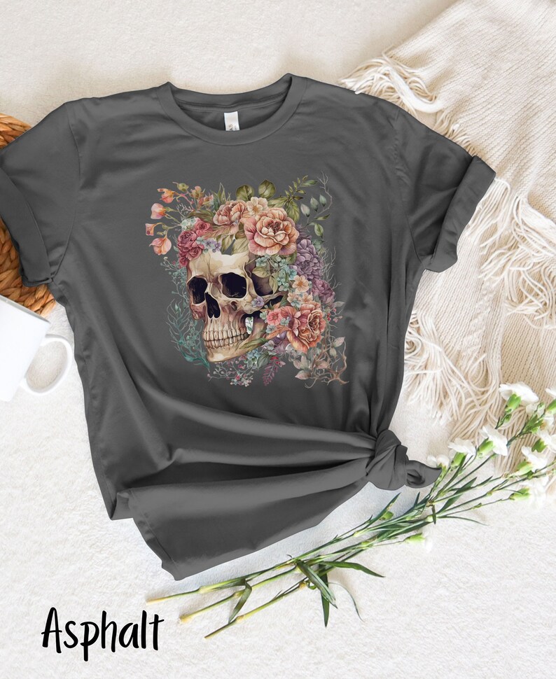 May include: A dark gray t-shirt with a floral skull design. The skull is surrounded by pink, purple, and white flowers.