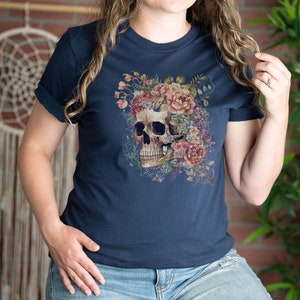 May include: A navy blue t-shirt with a floral skull graphic. The skull is surrounded by pink, white, and purple flowers.