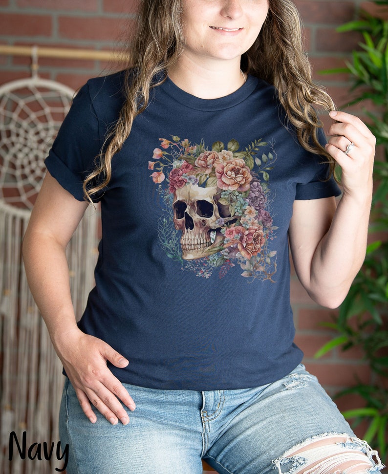 May include: A navy blue t-shirt with a floral skull graphic. The skull is surrounded by pink, white, and purple flowers.
