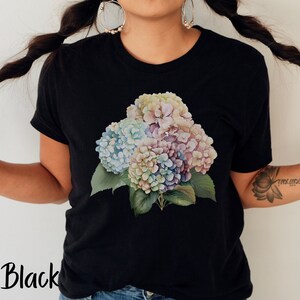 May include: Black t-shirt with a colorful floral print of hydrangeas. The flowers are in shades of pink, blue, and white.