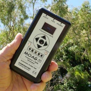 Może przedstawiać: Czarne urządzenie elektroniczne z ekranem wyświetlającym "Frequency in Hertz" trzymane w dłoni. Urządzenie posiada przyciski z etykietami "AUDIO", "PWR" i "PROBES". Widoczny jest również tekst "MOAG" i "Automatic Probe Test".