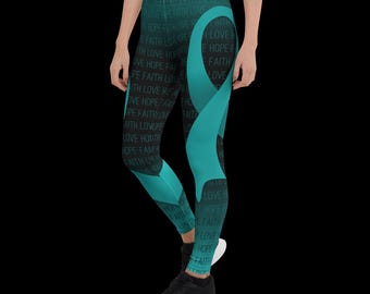 May include: Teal and black leggings with the words "HOPE FAITH LOVE" printed on the black sections. A teal ribbon design is on the front of the leggings. The leggings are worn by a person with black sneakers.