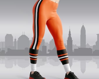 May include: Orange and black leggings with white stripes. The leggings have a sporty design and are perfect for working out or running errands.