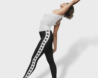 May include: Black leggings with a white stripe down the side, featuring a pattern of white stars. The leggings are worn with a white tank top and white ballet flats. The image is set against a plain white background.