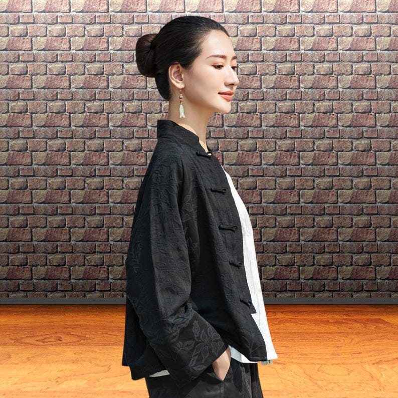 This black floral jacquard linen jacket offers a structured yet breathable layer for the autumn transition, blending traditional frog button details with modern fit. This piece uses the natural weight of flax linen. The "Deep Carbon Black" isn't a flat dye; the tonal jacquard weave adds a subtle dimension that becomes visible as you move. Functions as a soft blazer for the office or a meditative outer layer for weekend outings.