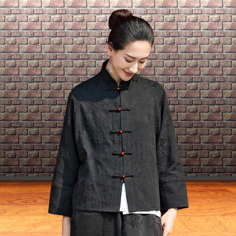 This black floral jacquard linen jacket offers a structured yet breathable layer for the autumn transition, blending traditional frog button details with modern fit. This piece uses the natural weight of flax linen. The "Deep Carbon Black" isn't a flat dye; the tonal jacquard weave adds a subtle dimension that becomes visible as you move. Functions as a soft blazer for the office or a meditative outer layer for weekend outings.