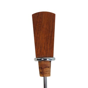 May include: A bottle stopper featuring a tapered, reddish-brown wooden handle with a visible grain pattern. A smooth, silver-toned metal ring separates the wooden top from the natural, light-brown cork base, which is attached to a thin metal stem.