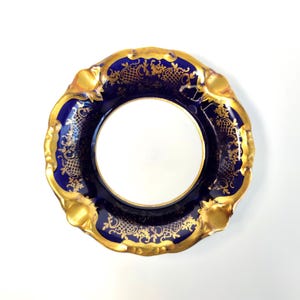 以下が含まれることがあります： 装飾的なパターンが施された青と金の磁器のソーサー。ソーサーは波状の縁取りがされており、お茶やコーヒーを提供するのに最適です。