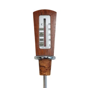 May include: A wine thermometer with a wooden handle featuring a vertical scale in Celsius from 5 to 25 degrees. The display includes labels for Cognac, Rotwein, Dessertwein, Weisswein, Sekt, and Branntwein. It has a cork stopper and a metal stem.