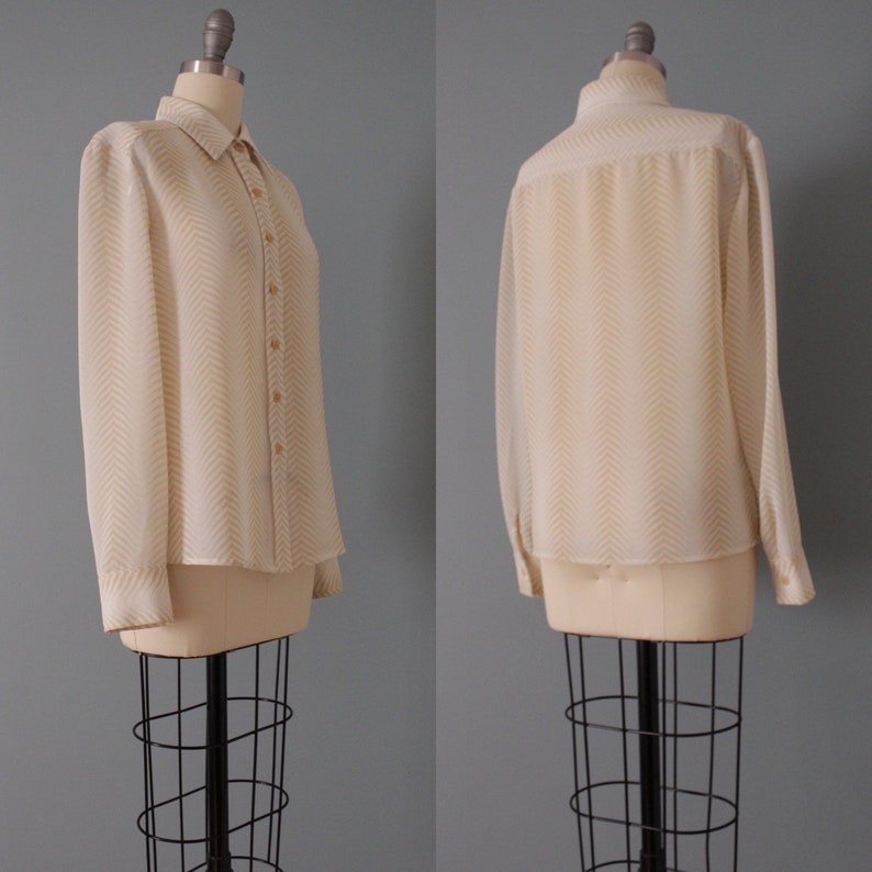 May include: A white and beige long-sleeved button-up shirt with a chevron pattern. The shirt is on a white mannequin.