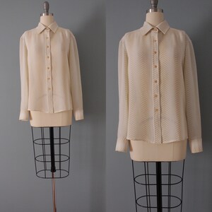 May include: A white long-sleeved button-down shirt with a chevron pattern in a light beige color.