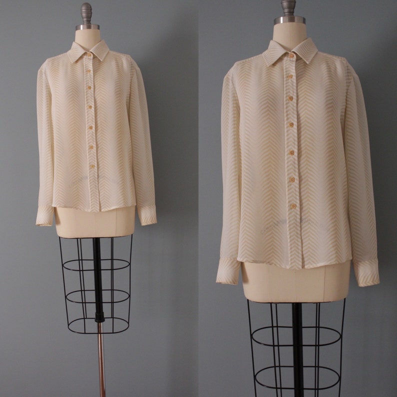 May include: A white long-sleeved button-down shirt with a chevron pattern in a light beige color.