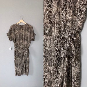 May include: A brown and white snake print midi dress with a wrap style and a tie at the waist.