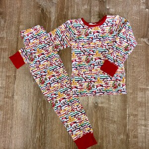 May include: A two-piece pajama set featuring a long-sleeve top and matching pants with a repeating pattern of Mickey Mouse wearing a Santa hat against a background of thin horizontal stripes in red, green, and white, finished with solid red cuffs.