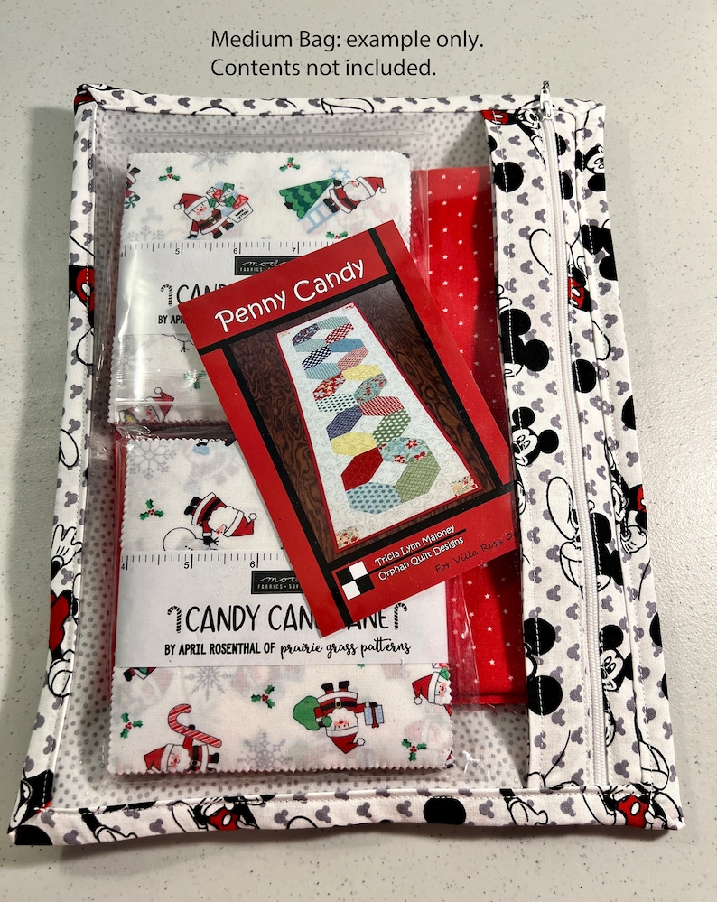 Puede incluir: Una bolsa blanca con cremallera con un patr&oacute;n de Mickey Mouse. La bolsa est&aacute; abierta y contiene una tela roja, una bolsa de pl&aacute;stico transparente con cuadrados de tela y un patr&oacute;n impreso para una colcha Penny Candy. El patr&oacute;n se titula "Penny Candy" y es de Tricia Lynn Maloney, Orphan Quilt Designs. Los cuadrados de tela son para una colcha Candy Cane de April Rosenthal de Prairie Grass Patterns.