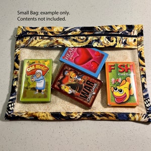 Puede incluir: Una peque&ntilde;a bolsa con cremallera con un estampado abstracto colorido. La bolsa est&aacute; abierta y contiene cinco juegos de cartas: Old Maid, Hearts, War, Fish y otro juego de cartas con un dise&ntilde;o rojo y azul. La bolsa est&aacute; hecha de tela y tiene una ventana de pl&aacute;stico transparente.