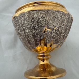 May include: A decorative chalice featuring a textured, crackled gray and white pattern on the bowl, accented with a polished gold rim, a gold base, and gold leaf-shaped detailing extending from the stem onto the lower portion of the bowl.