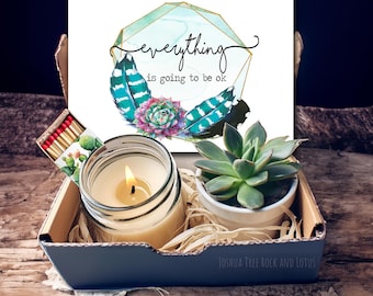 May include: A gift box filled with a candle, a succulent plant, and a card that reads "everything is going to be ok". The card features a watercolor design of feathers and a succulent.