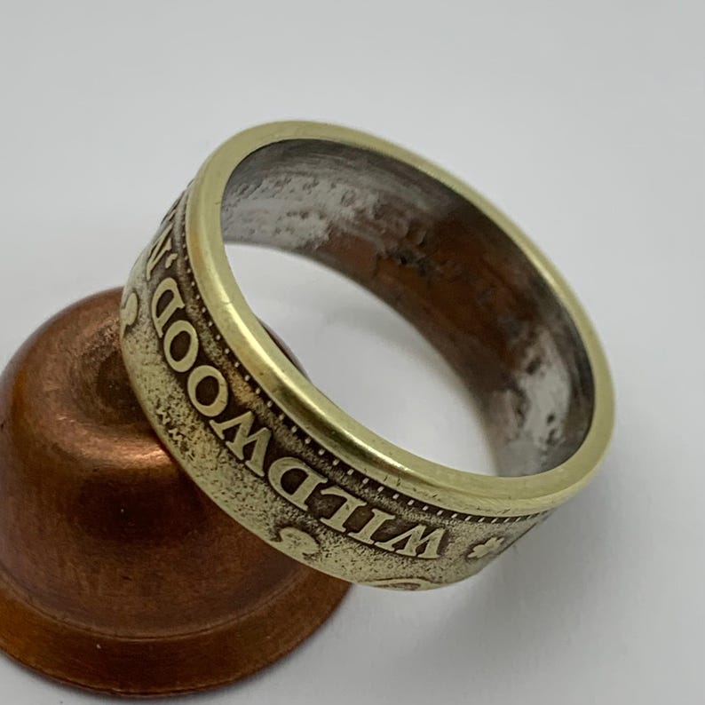 May include: A gold-toned ring made from a coin with the inscription "WILDWOOD" around the band.
