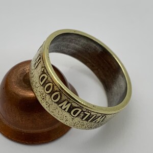 May include: A gold-colored ring made from a coin with the words "WILDWOOD" engraved around the band.