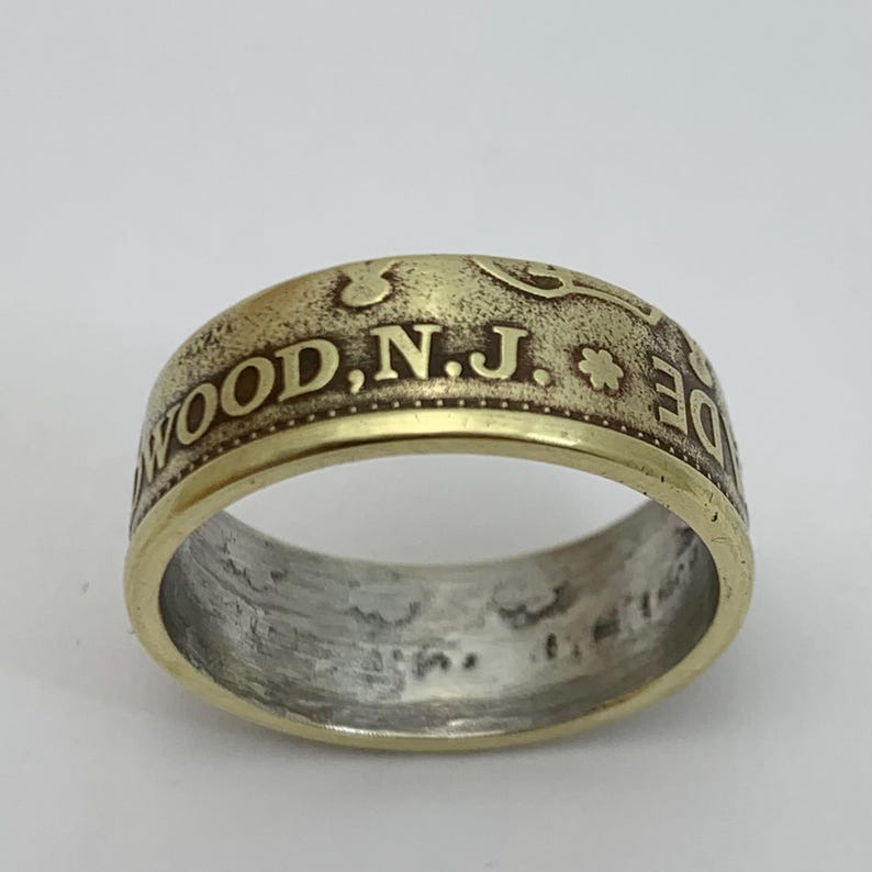 May include: A gold-toned ring made from a coin with the inscription "WOOD, N.J." on the band.