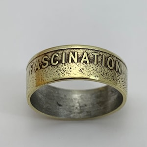 May include: A gold-toned ring with the word "FASCINATION" engraved on the band.