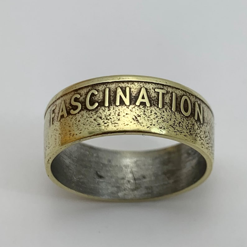 May include: A gold-toned ring with the word "FASCINATION" engraved on the band.