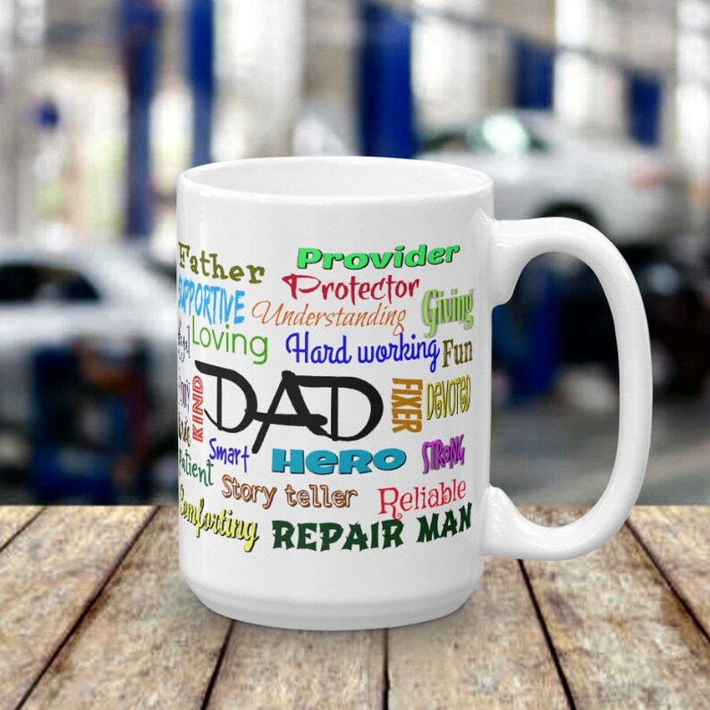 May include: White ceramic mug with a colorful word cloud design that reads "Provider, Protector, Giving, Understanding, Hard working, Fun, Dad, Fixer, Devoted, Strong, Smart, Hero, Story teller, Reliable, Repair Man".