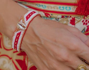 Adjustable sliding bracelet woven with Miyuki Delica seed beads decorated with a golden cowrie shell in the center