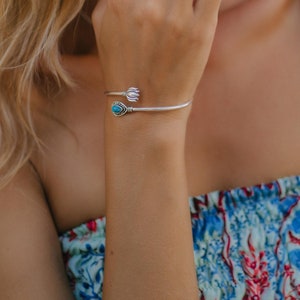 May include: A silver ring and bracelet set with turquoise accents. The ring features a teardrop-shaped turquoise stone surrounded by a decorative silver setting. The bracelet has a similar turquoise stone and a floral design.
