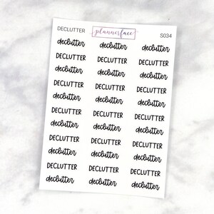 May include: A sheet of planner stickers with the word "declutter" repeated multiple times in a handwritten font. The stickers are white with black lettering and are arranged in three columns.