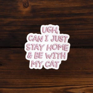 May include: White sticker with pink text that reads "Ugh, Can I Just Stay Home & Be With My Cat".