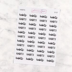 Puede incluir: Hoja de pegatinas blanca con la palabra "habits" en fuente manuscrita, repetida varias veces. La marca "plannerface" está en un recuadro rosa en la parte superior. La hoja de pegatinas tiene el código "S157".