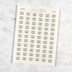 May include: A sheet of stickers with a cream background featuring numerous small, black outline drawings of open books. The word "BOOK" is printed at the top left, with "plannerface" in a pink rectangle and "T007" at the top right.