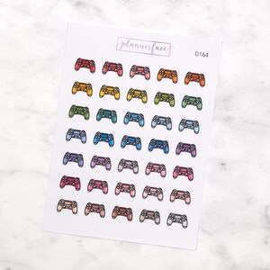 Puede incluir: Una hoja de pegatinas de mandos de juego de colores. Las pegatinas están dispuestas en filas de seis, con cada fila presentando un color diferente. Los colores incluyen rojo, naranja, amarillo, verde, azul, morado, rosa, marrón y beige. Las pegatinas son todas del mismo tamaño y forma, y presentan un contorno simple de un mando de juego.