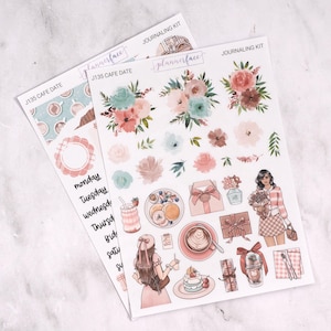 Può includere: Due fogli di adesivi per il journaling. Un foglio presenta un tema caffè con tazze e croissant. L'altro foglio presenta composizioni floreali, illustrazioni di cibo e una donna con fiori. Il testo include "J135 CAFE DATE" e "JOURNALING KIT".