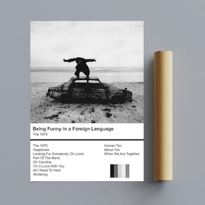 Può includere: Copertina dell'album in bianco e nero per l'album di The 1975 "Being Funny in a Foreign Language". La copertina dell'album presenta una persona in piedi su un'auto su una spiaggia.