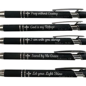 May include: Five black pens with silver accents and a cross design. Each pen has a different inspirational quote and bible verse engraved on it. The quotes are "Pray without ceasing", "God is my refuge", "I am with you always", "Saved by His Grace", and "Let your light shine".