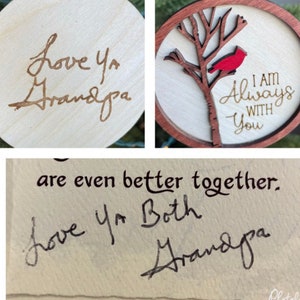 May include: Two wooden ornaments with handwritten messages. The first ornament is round and says "Love ya Grandpa". The second ornament is round and features a red cardinal on a branch with the text "I am Always With You".