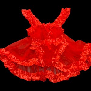 May include: A bright red lingerie set with a ruffled design. The set is made of a sheer, flowing fabric with multiple layers of ruffles along the edges and straps. A satin bow is at the centre, adding a touch of elegance.