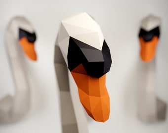 Peut inclure: Trois cygnes en origami en papier. Les cygnes sont blancs avec des accents noirs et orange. Les cygnes sont disposés en rangée, le cygne du milieu étant au premier plan.