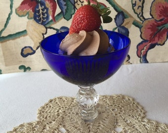 May include: A blue glass dessert dish with a swirl of chocolate mousse topped with a fresh strawberry.