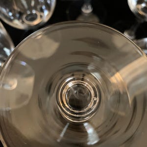 Puede incluir: Una copa de vino de vidrio transparente con una copa ancha y un tallo largo. La copa est&aacute; vac&iacute;a y el tallo es visible.